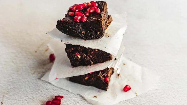 No-Cook Pomegranate Stuffed Brownies stacked with pieces of parchment paper