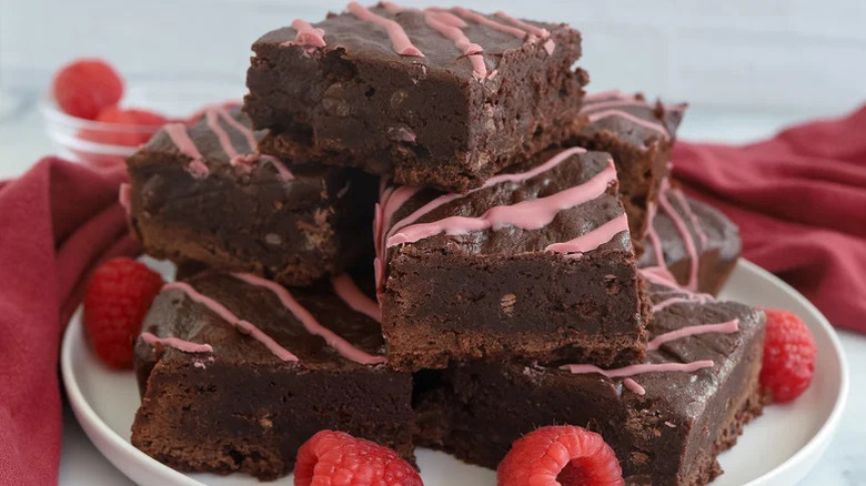 Valentine's Day Raspberry Brownies stacked on white plate with raspberries
