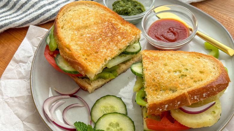 Bombay sandwich on plate with cucumber and red onion slices