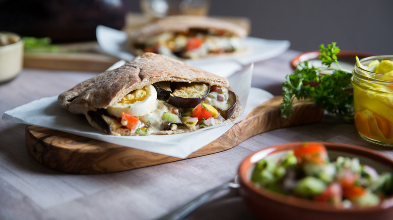 Sabich stuffed pita sandwich on wooden board