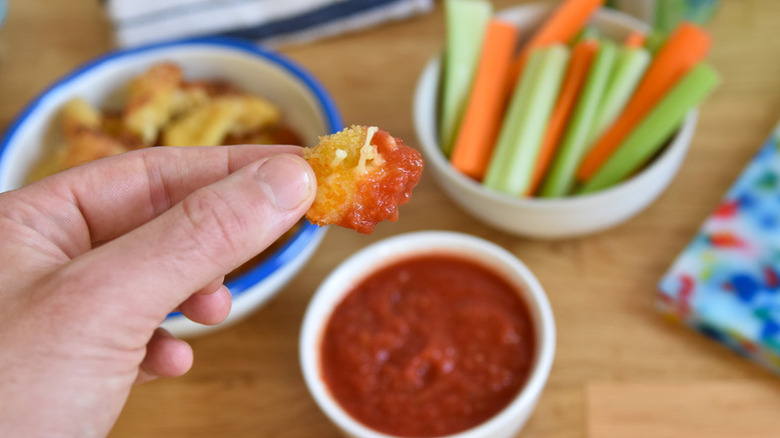 Dipping cheese curd into bowl of marinara