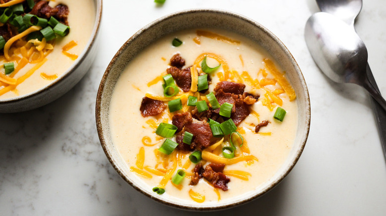 Bowl of potato soup topped with cheese, bacon and green onion
