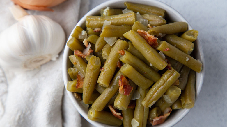 Bowl of cooked green beans with bacon and onion