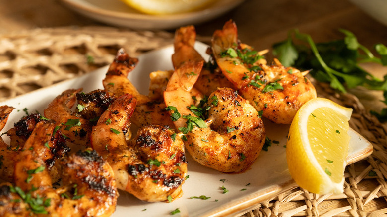 Grilled shrimp on plate with herb garnish and lemon slice