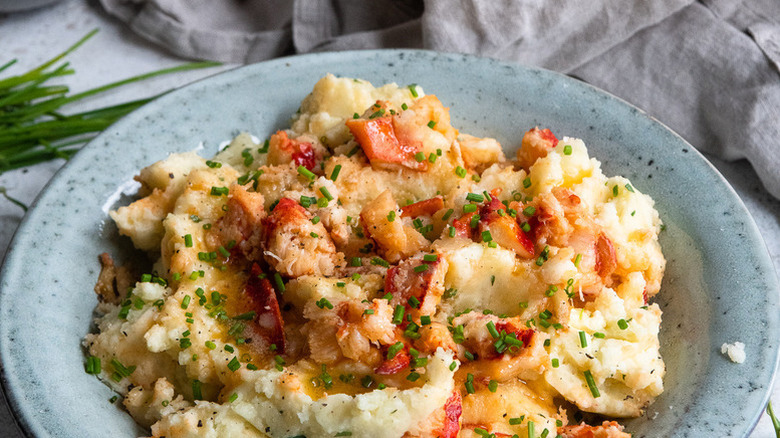 Lobster mashed potatoes in blue bowl, topped with fresh chives
