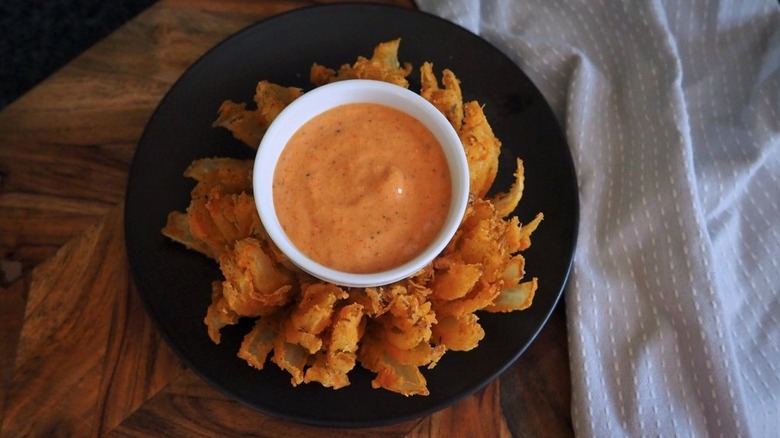 Crispy bloomin' onion served on plate with creamy orange dip