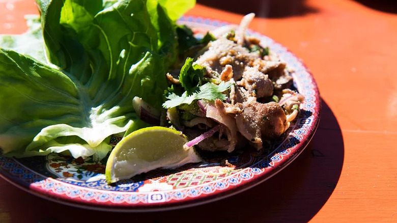 Malaysian Pork Lettuce Wraps with herbs and lime on colorful plate