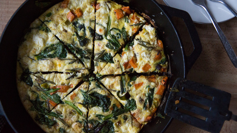 Sliced sweet potato and greens frittata in skillet