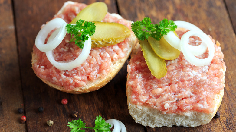 Mettbrötchen with pickes and onions on wood table