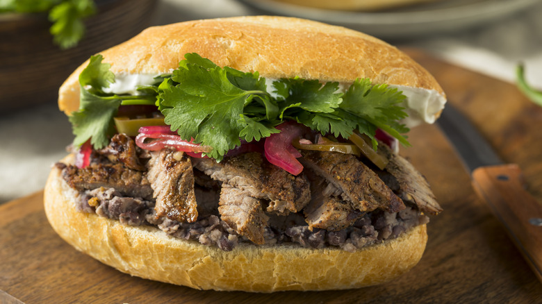 Torta on wooden board with knife, sliced bread and cilantro
