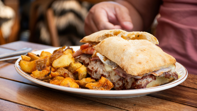 Chivito sandwich on plate on wooden table