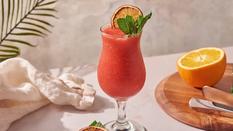Frozen Strawberry Daiquiri Cocktail in large glass with citrus and mint garnish
