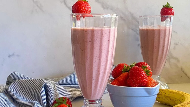 Two Strawberry Cinnamon Smoothies in smoothie glasses with strawberry garnish