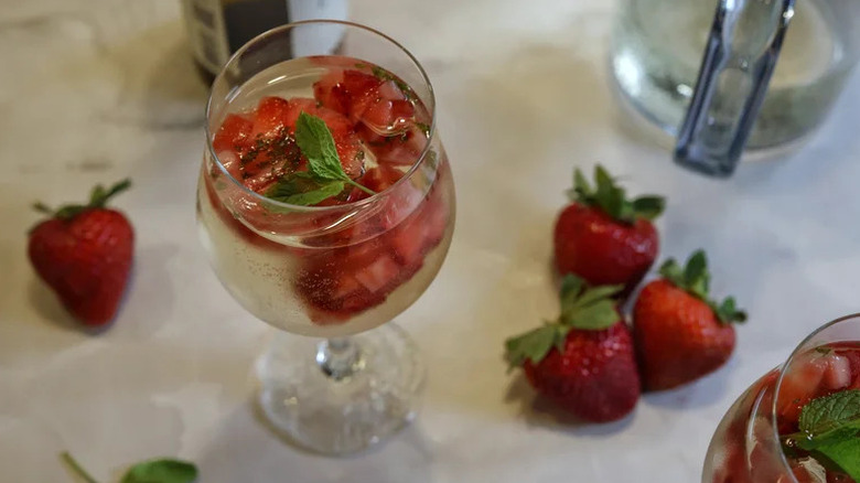 Strawberry Summer White Wine Spritzer in tall wine glass with strawberries on counter