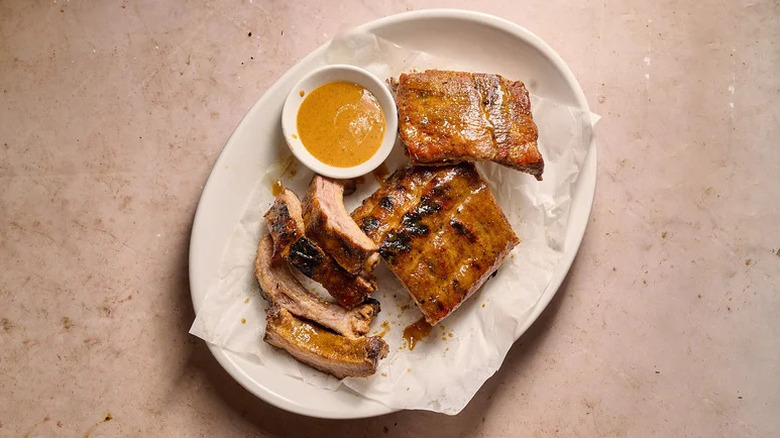 Baby Back Ribs with Honey Mustard BBQ Sauce on white plate with bowl of sauce
