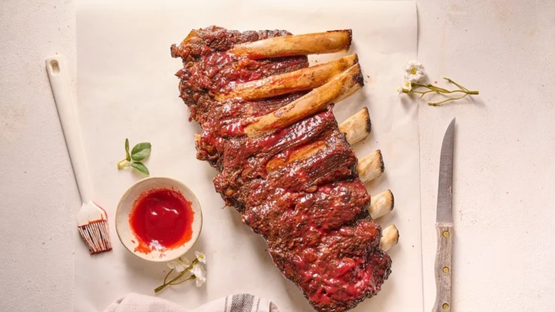 Sweet, Spicy, Smoky Raspberry Chipotle Ribs on parchment paper with bowl of sauce