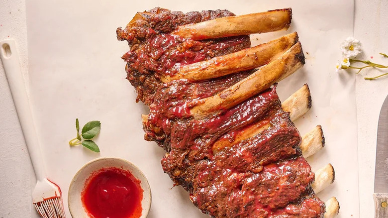 Sweet, Spicy, Smoky Raspberry Chipotle Ribs on parchment paper with bowl of sauce