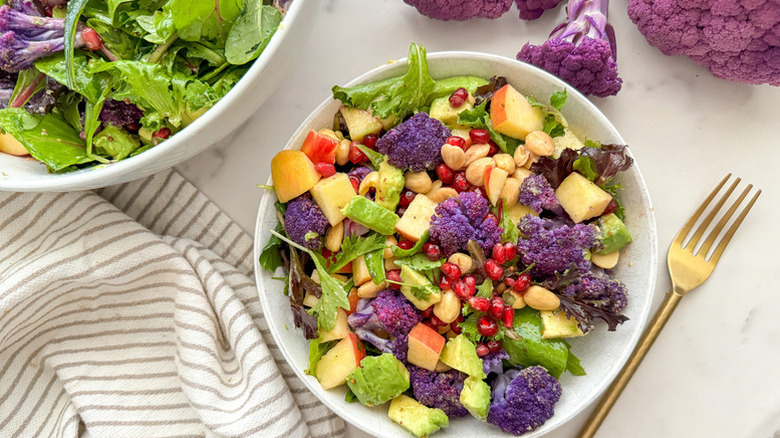 Purple cauliflower and apple salad in white bowl