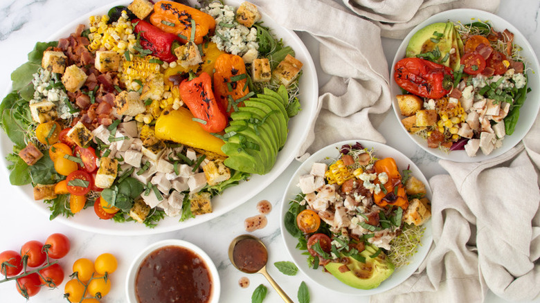 Colorful chicken, bacon, and veggie salad on serving platter and in bowls