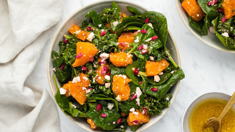 Roasted butternut squash, spinach, feta, and pomegranate salad in bowl