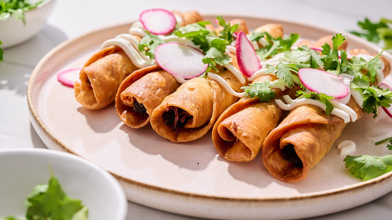 flautas on a plate with radishes and cilantro