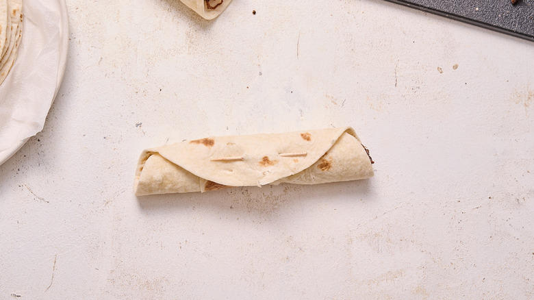 rolled flauta sealed with toothpick on table