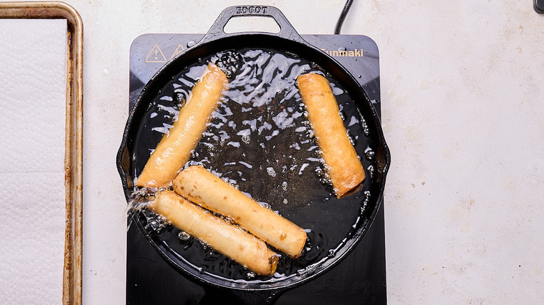 frying flautas in a skillet of oil