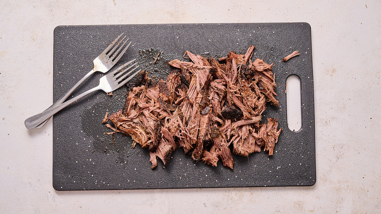 shredding beef on a cutting board