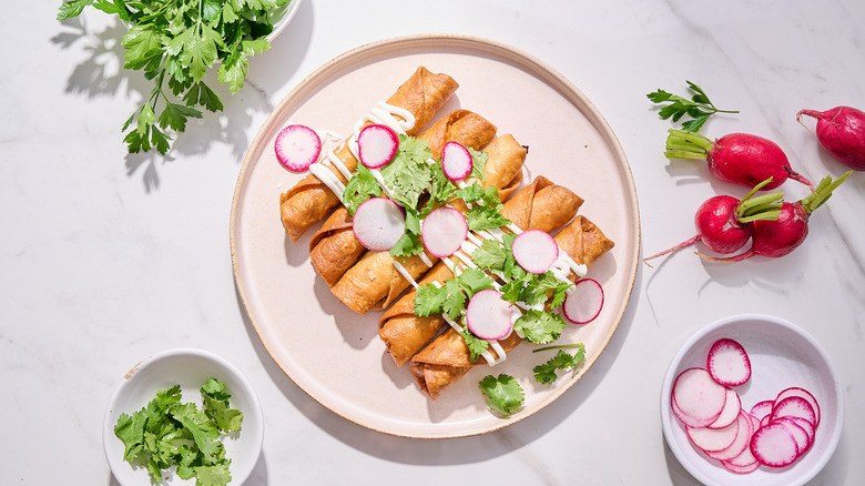 flautas on a plate with cilantro and radishes