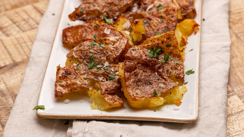 air-fried garlic smashed potatoes on a white plate over a cloth