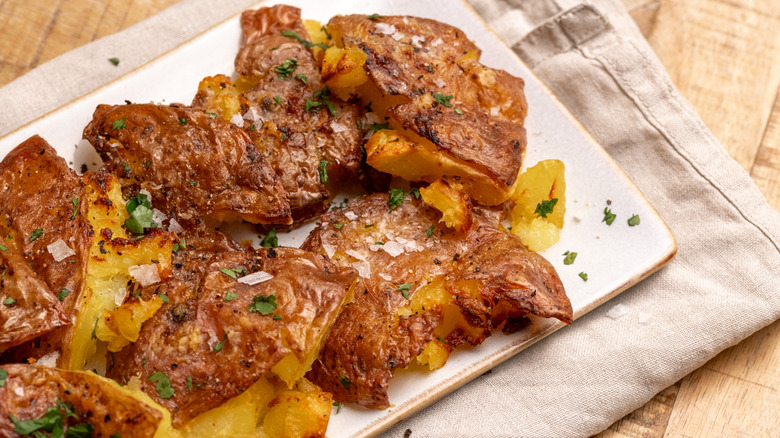air-fried garlic smashed potatoes on a white plate on top of a cloth