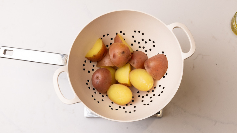 chopped cooked red potatoes in a colander over a pot