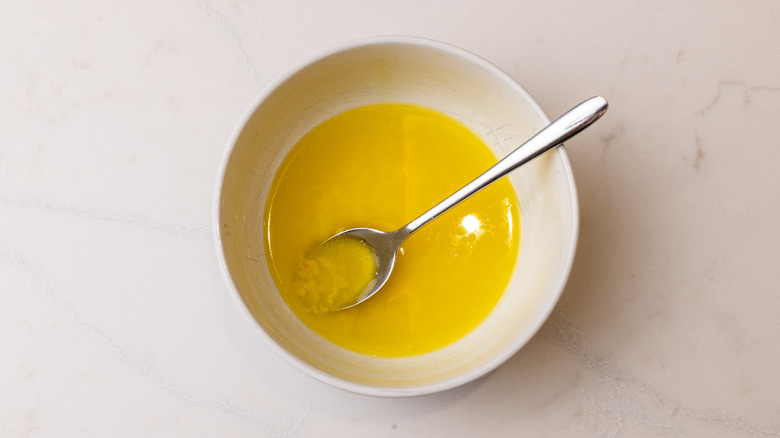 garlic butter and oil mixture in a white bowl with spoon inside