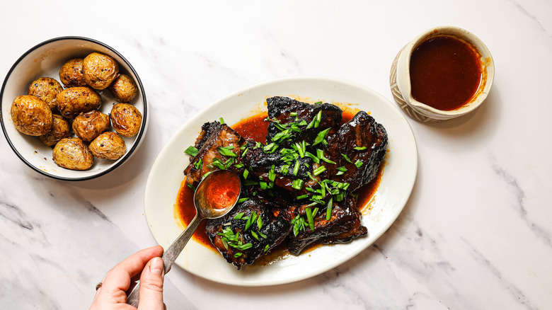 Pouring sauce over short ribs