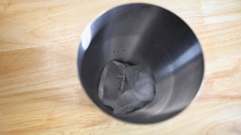cocktail shaker with ice in it on light wood table
