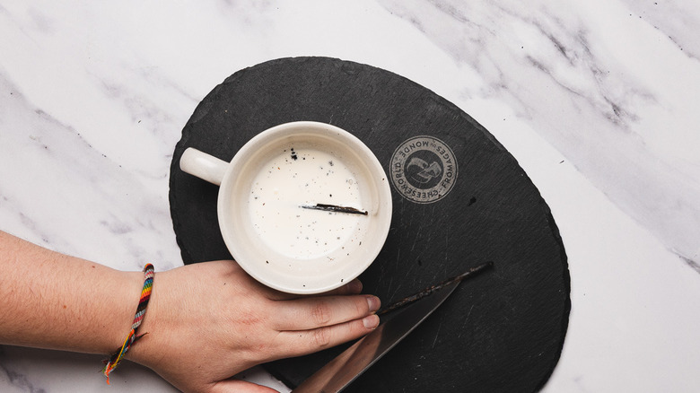 Adding split vanilla pod to cup with cream