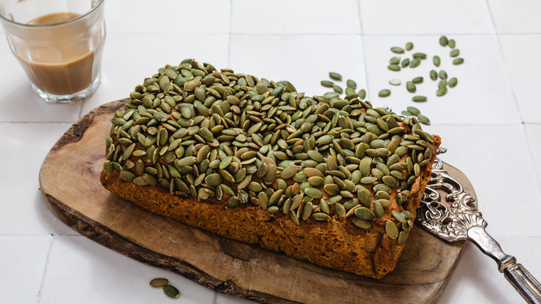 Pumpkin bread on a cutting board next to cup of coffee