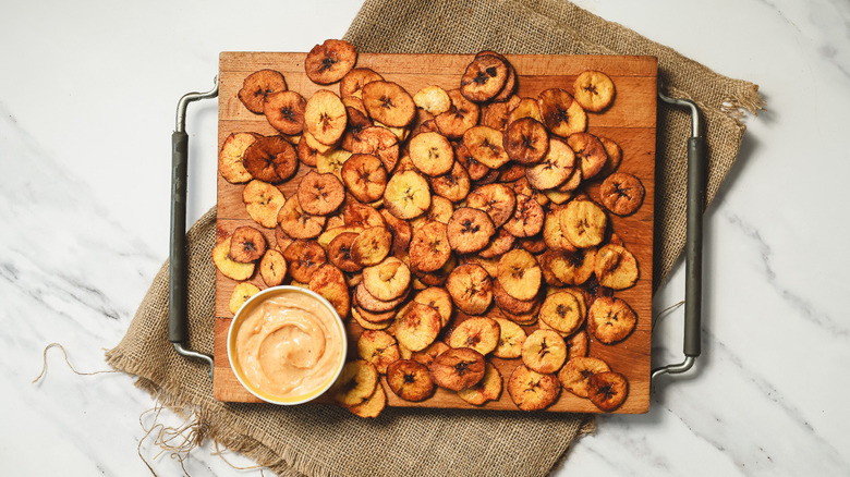 Cooling plantain chips on cutting board with sauce