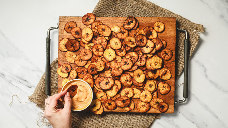 Hand dipping a plantain chip into sauce
