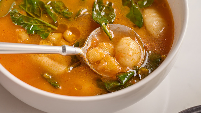 gnocchi soup on a spoon in a bowl