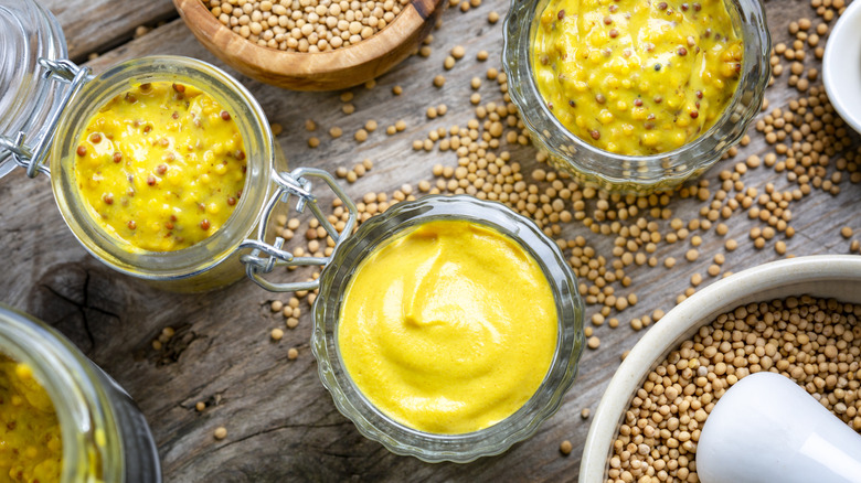 Jars of various mustards surrounded by mustard seeds