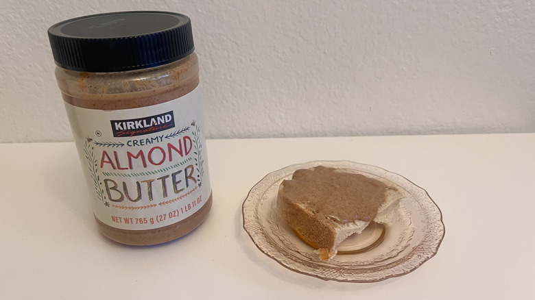 Jar of Kirkland Signature Creamy Almond Butter with piece of bread