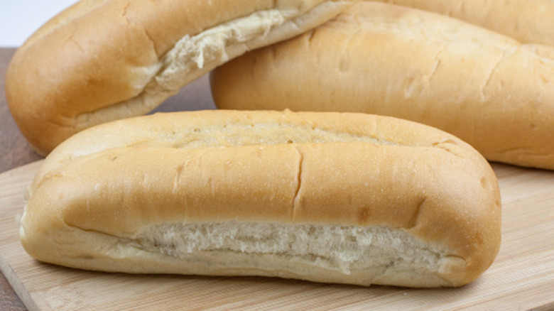 Sandwich bread rolls on cutting board.