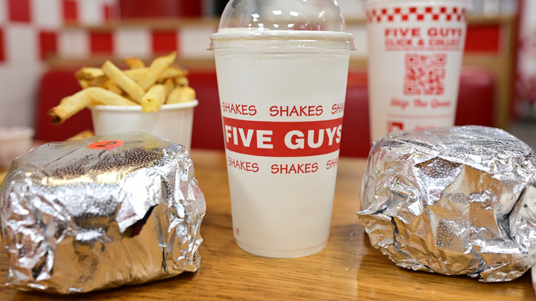 Five Guys burgers, fries, and drinks on a table inside the restaurant