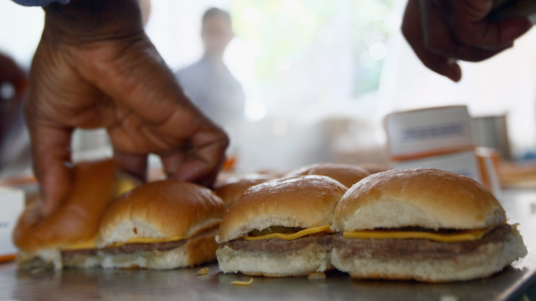 A cook preparing White Castle sliders on the griddle