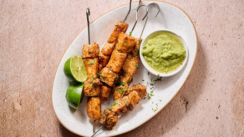 Spicy salmon skewers on plate with salsa verde