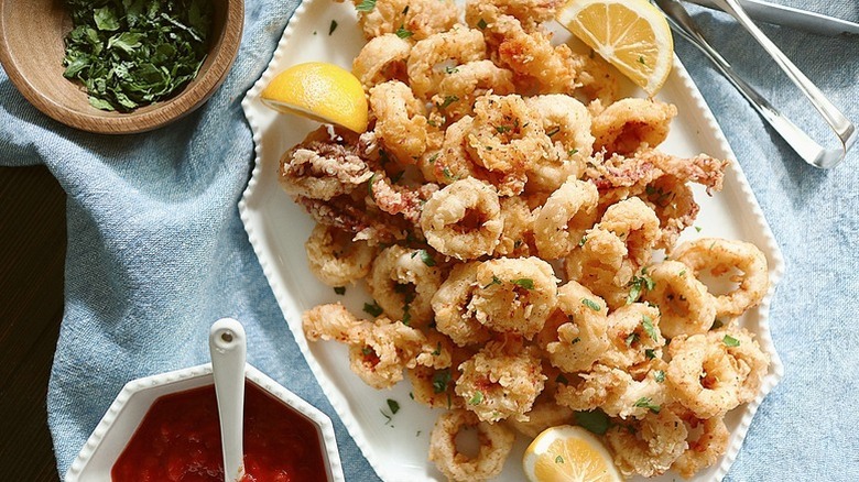 Pile of calamari on serving platter with lemon wedges
