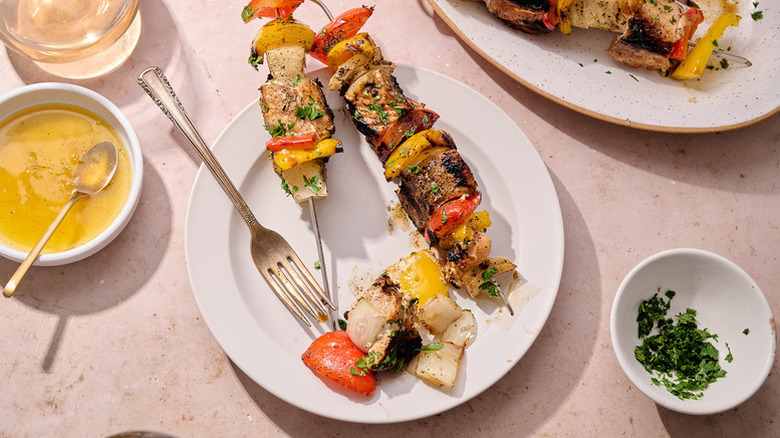 Salmon and red pepper skewers on plate next to bowl of honey glaze