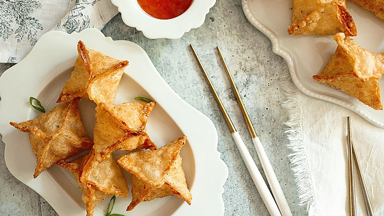 Crab rangoon on serving plates with chopsticks