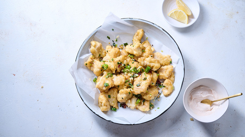 Salt and pepper fried catfish pieces in parchment-lined bowl